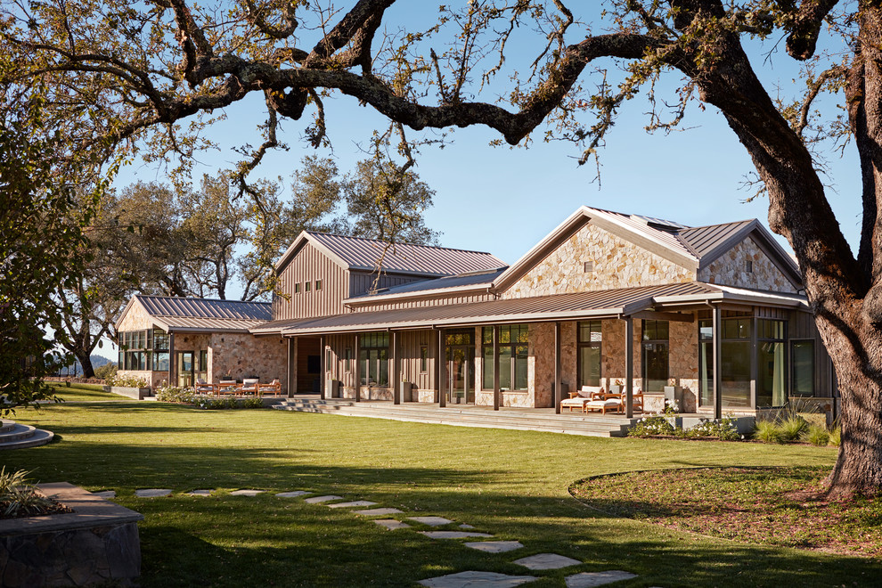 Esempio della villa beige country con rivestimenti misti, tetto a capanna, copertura in metallo o lamiera e tetto grigio