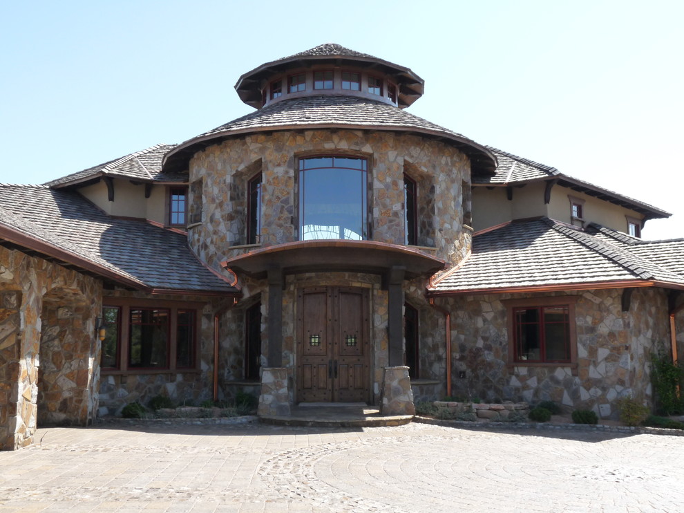 Cette photo montre une très grande façade de maison beige montagne en pierre à un étage avec un toit à deux pans.