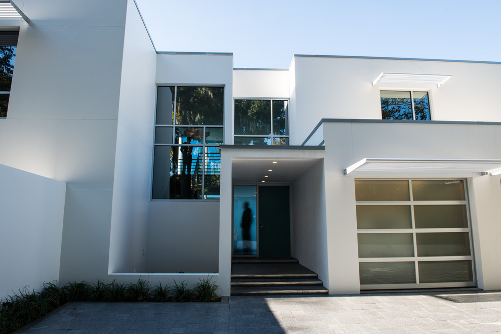 На фото: огромный, трехэтажный, белый дом в стиле модернизм с облицовкой из цементной штукатурки и плоской крышей с