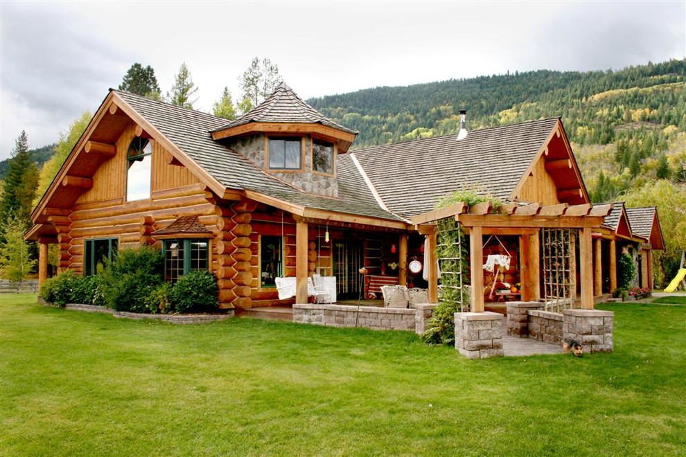 Стильный дизайн: деревянный, коричневый дом среднего размера в стиле рустика с разными уровнями, двускатной крышей и крышей из гибкой черепицы - последний тренд