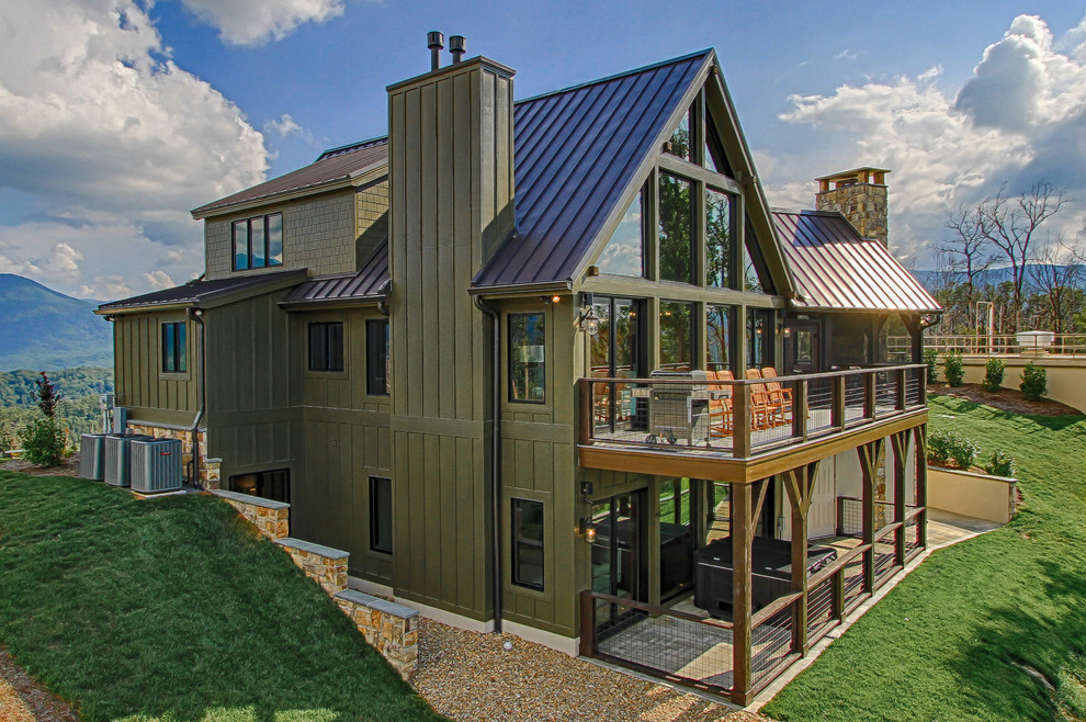 Immagine della villa verde rustica a due piani con rivestimento con lastre in cemento e copertura in metallo o lamiera