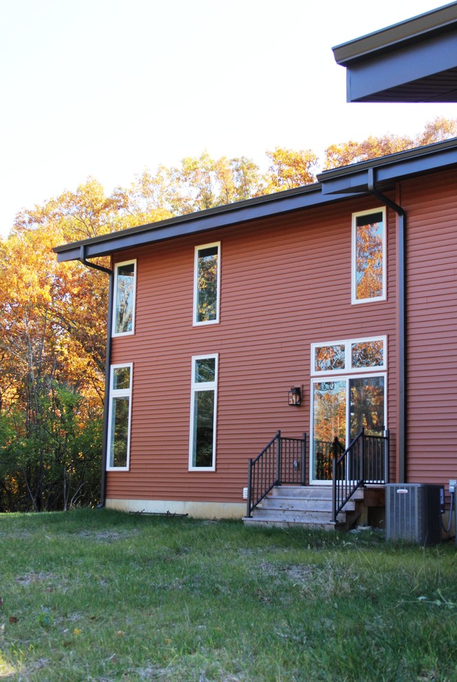 Immagine della facciata di una casa rossa moderna a due piani con rivestimento in vinile e copertura a scandole