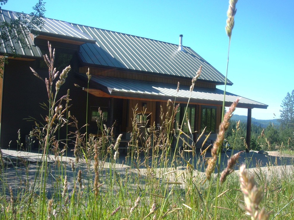 На фото: большой, двухэтажный, деревянный, коричневый частный загородный дом в стиле рустика с вальмовой крышей и металлической крышей