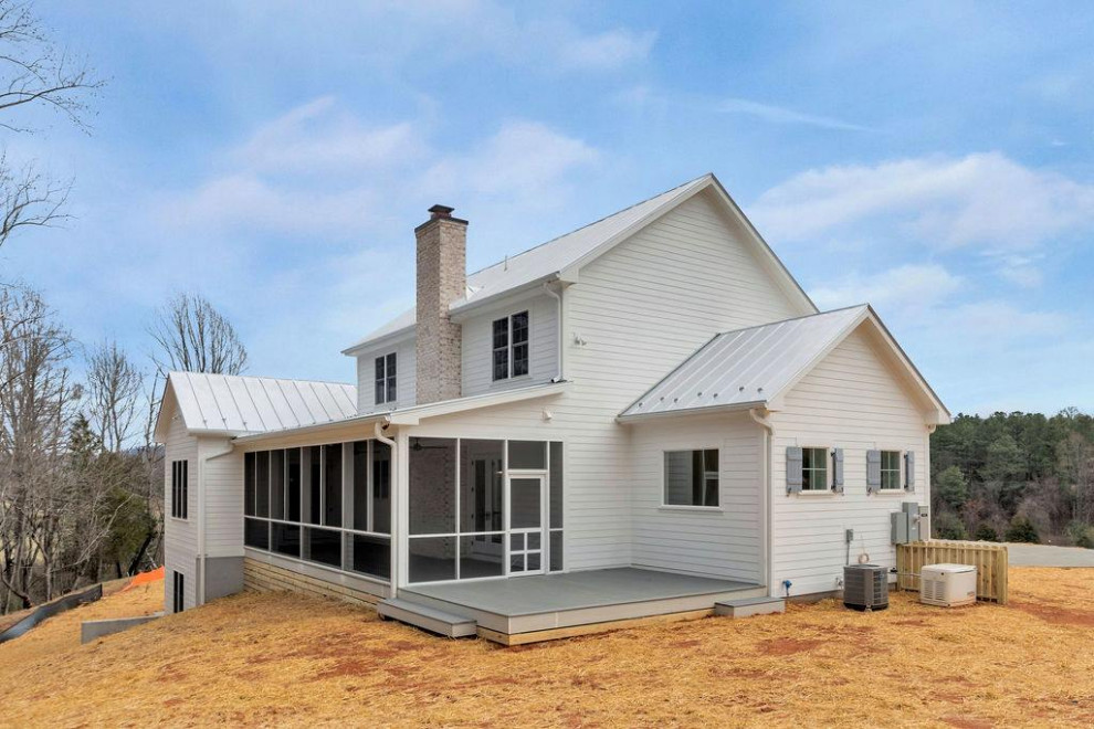 Ejemplo de fachada de casa blanca de estilo de casa de campo con revestimiento de aglomerado de cemento y tejado de metal