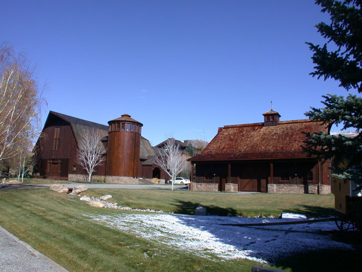 Esempio della facciata di una casa grande marrone country a due piani con rivestimento in legno e tetto a mansarda