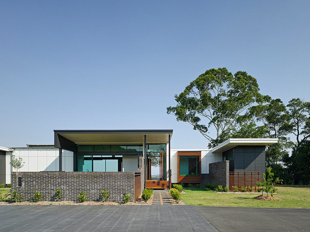 Foto på ett funkis flerfärgat hus, med allt i ett plan, blandad fasad och platt tak