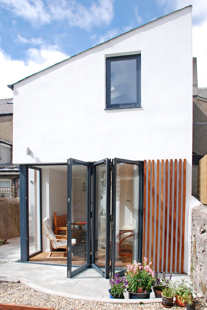 Réalisation d'une façade de maison blanche minimaliste de taille moyenne et à un étage avec un toit plat.