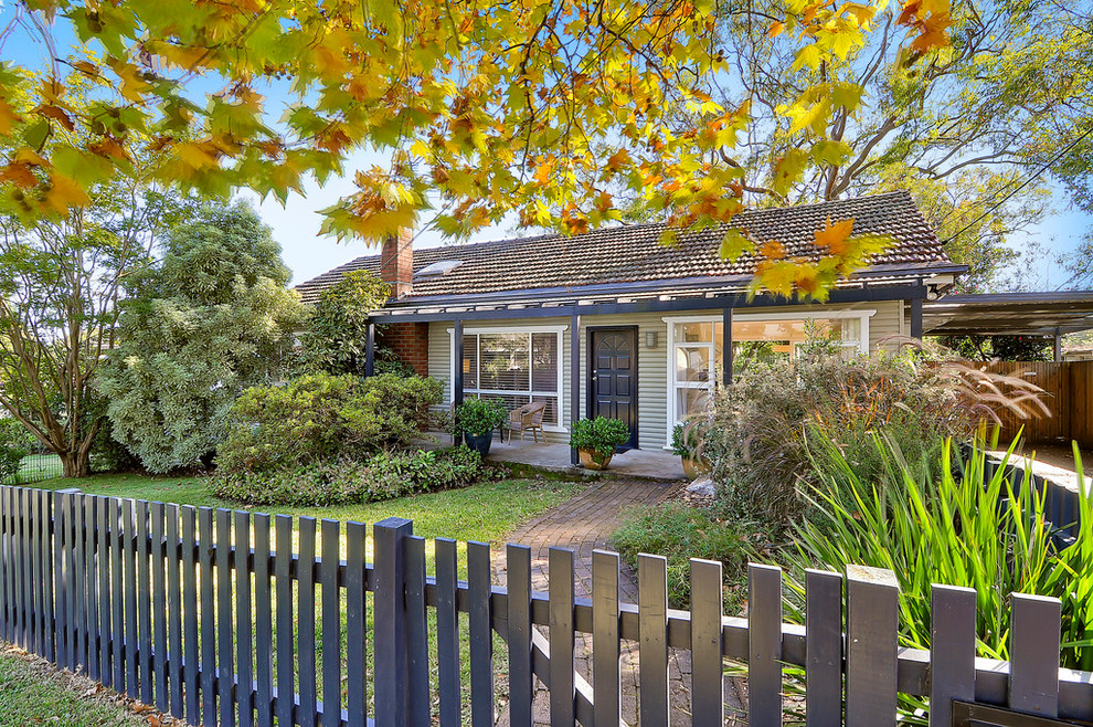 Small and beige modern bungalow detached house in Sydney with wood cladding and a tiled roof.
