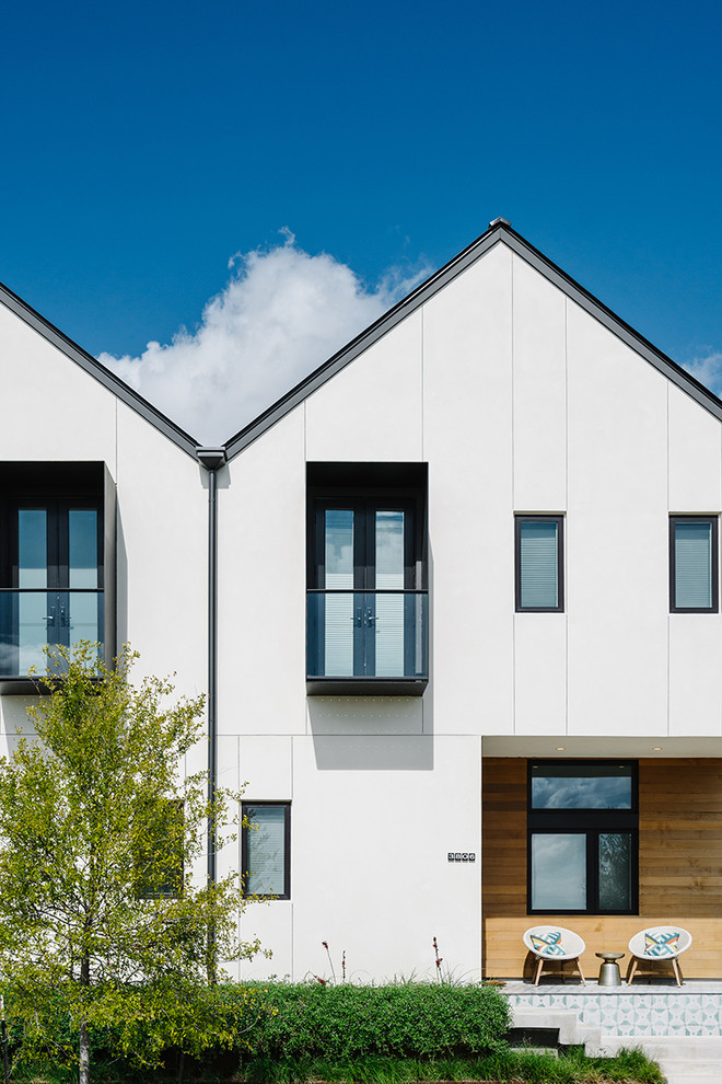 Cette image montre une façade de maison blanche nordique de taille moyenne et à un étage avec un revêtement en vinyle et un toit à deux pans.