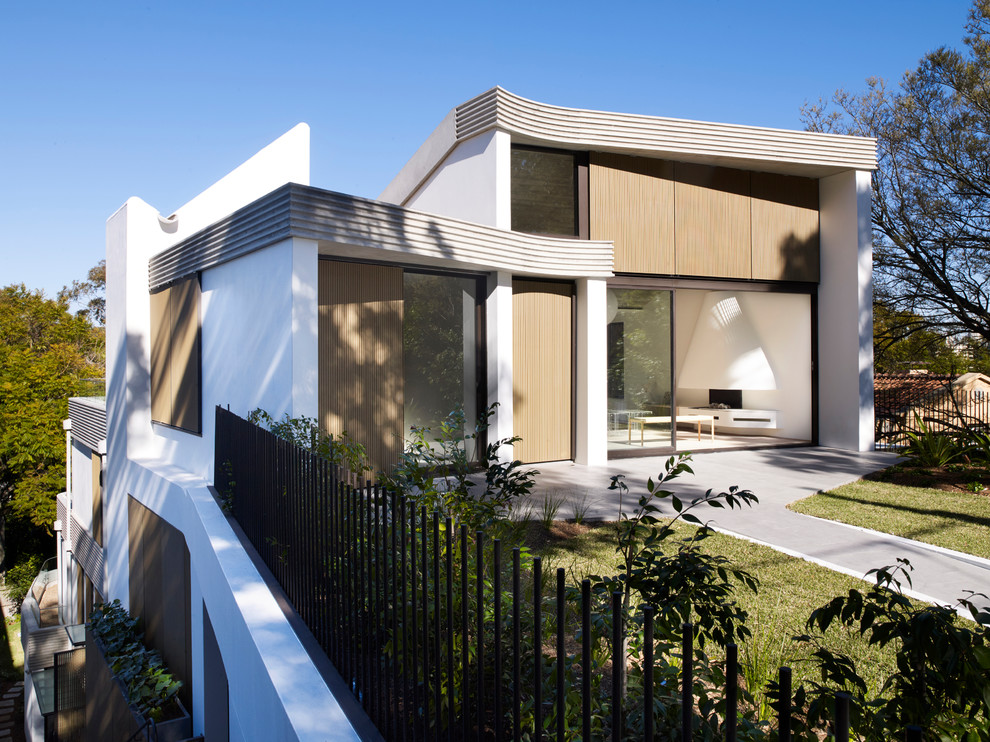 Cette photo montre une façade de maison blanche moderne à deux étages et plus avec un revêtement mixte et un toit plat.