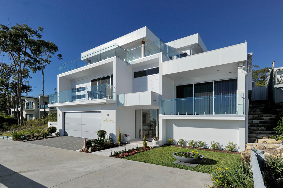 Exempel på ett mycket stort modernt vitt hus, med två våningar, fiberplattor i betong och platt tak