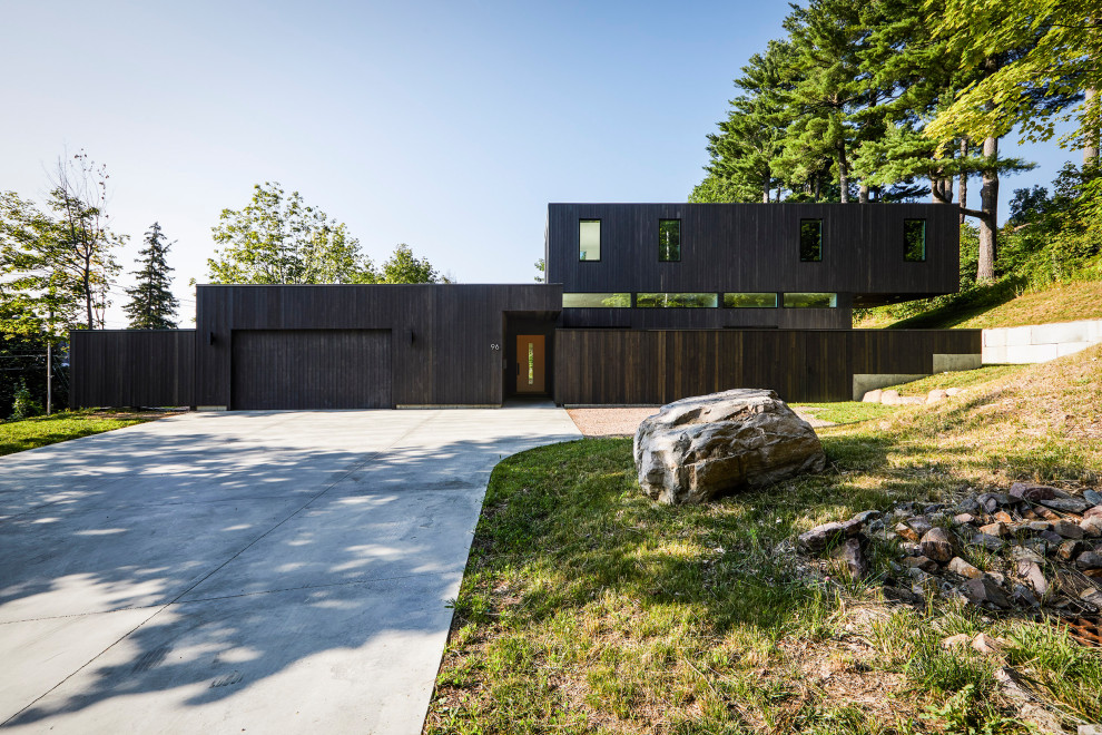 На фото: двухэтажный, деревянный, черный частный загородный дом среднего размера в стиле модернизм с плоской крышей с