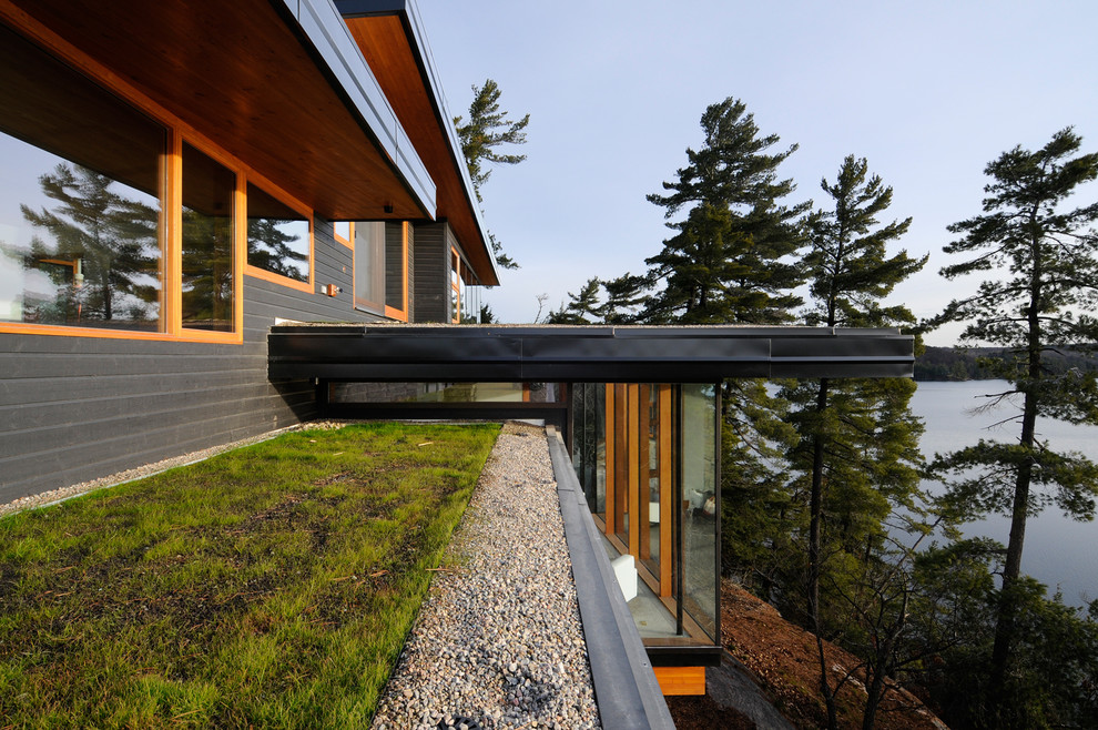 Immagine della villa contemporanea a due piani con rivestimento in legno, tetto piano e copertura in metallo o lamiera
