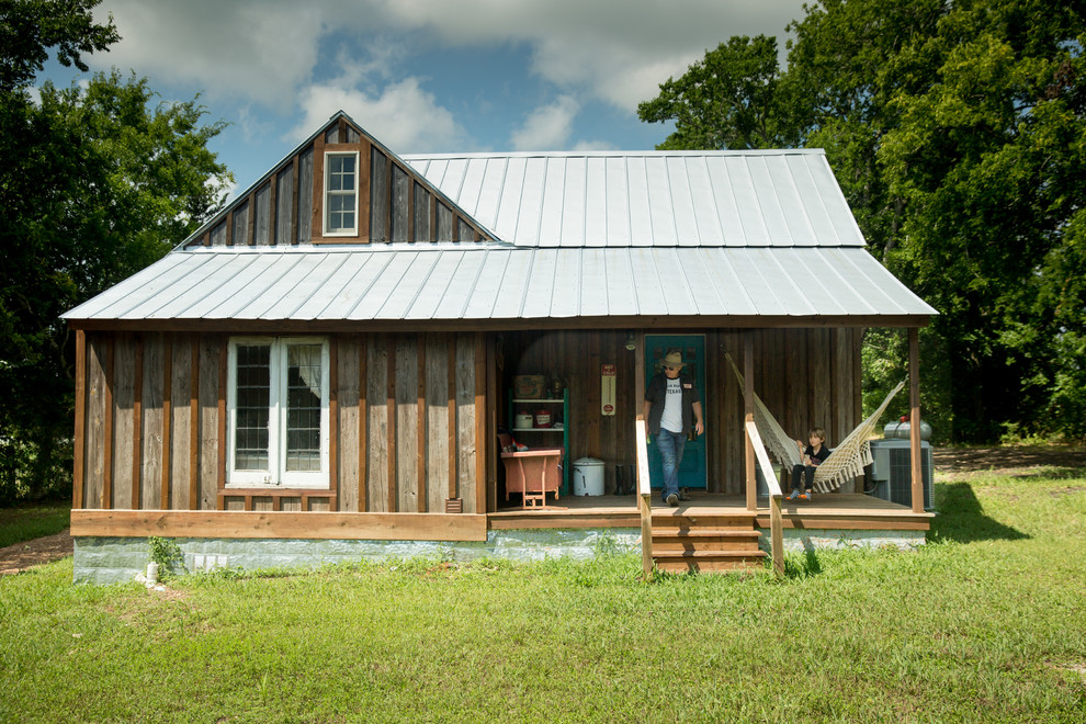 Imagen de fachada de casa marrón de estilo de casa de campo de una planta con revestimiento de madera, tejado a dos aguas y tejado de metal