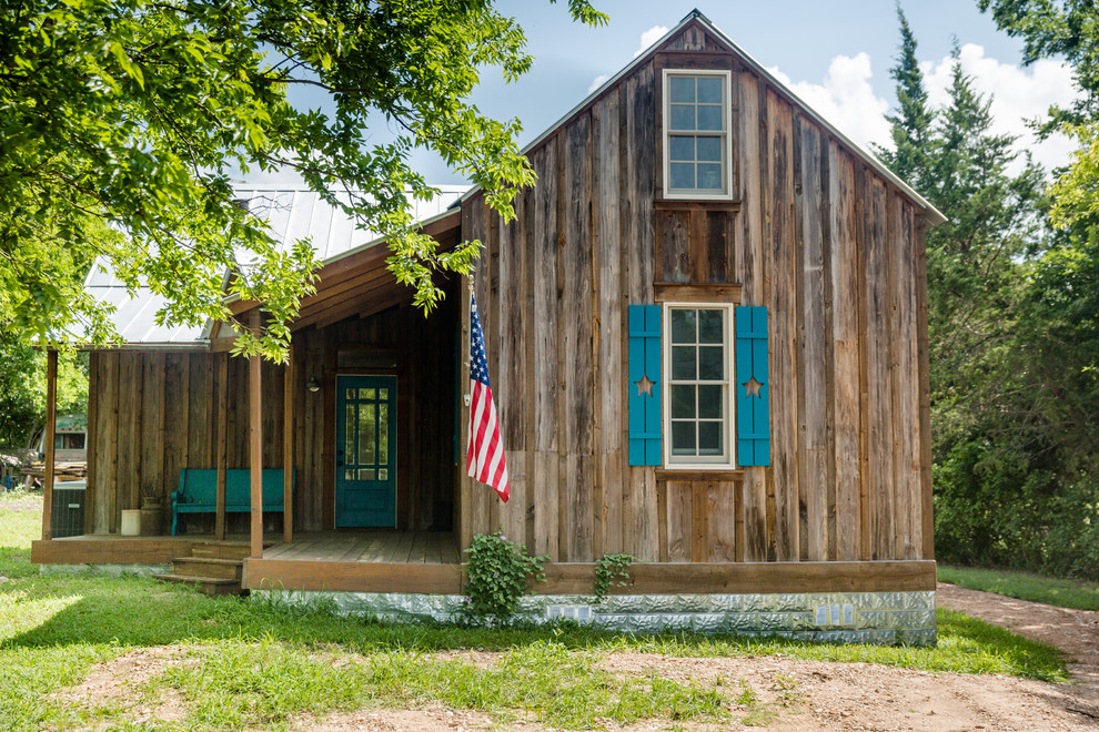 Foto della villa marrone country a due piani con rivestimento in legno, tetto a capanna e copertura in metallo o lamiera