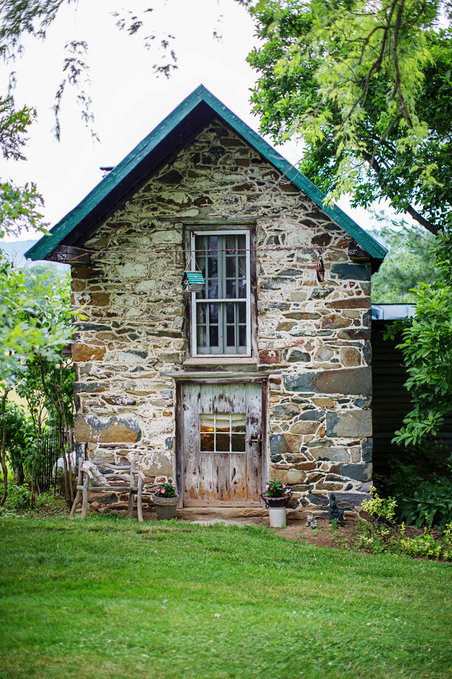 Esempio della facciata di una casa country con rivestimento in pietra e tetto a capanna