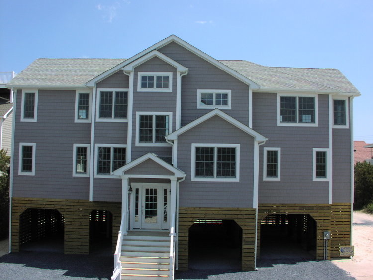 Modelo de fachada de casa gris marinera grande de tres plantas con revestimiento de vinilo, tejado a dos aguas y tejado de teja de madera