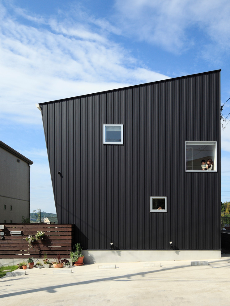 Idées déco pour une façade de maison noire et métallique contemporaine à un étage avec un toit en appentis.