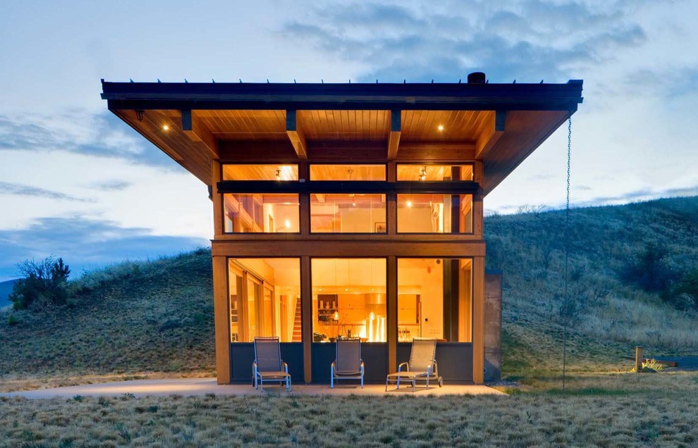 Cette image montre une façade de maison grise en bois à un étage avec un toit en appentis et un toit en métal.