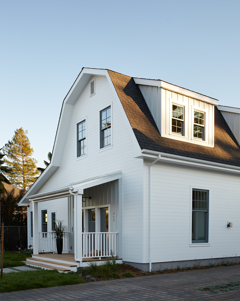 Esempio della facciata di una casa bianca country a due piani di medie dimensioni con rivestimento in legno e tetto a mansarda