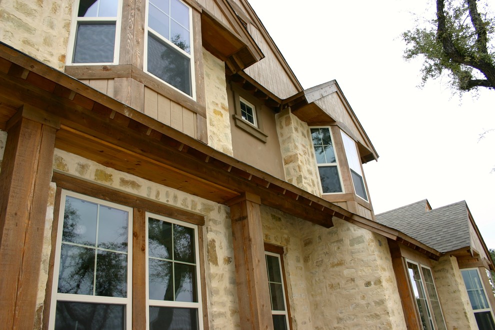 Diseño de fachada de casa beige campestre grande de dos plantas con revestimientos combinados, tejado a dos aguas y tejado de teja de madera
