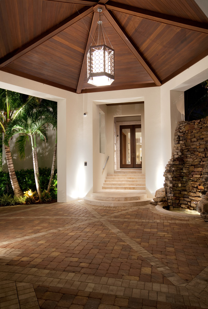 Ejemplo de fachada beige tropical de tamaño medio de dos plantas con revestimientos combinados y tejado a dos aguas
