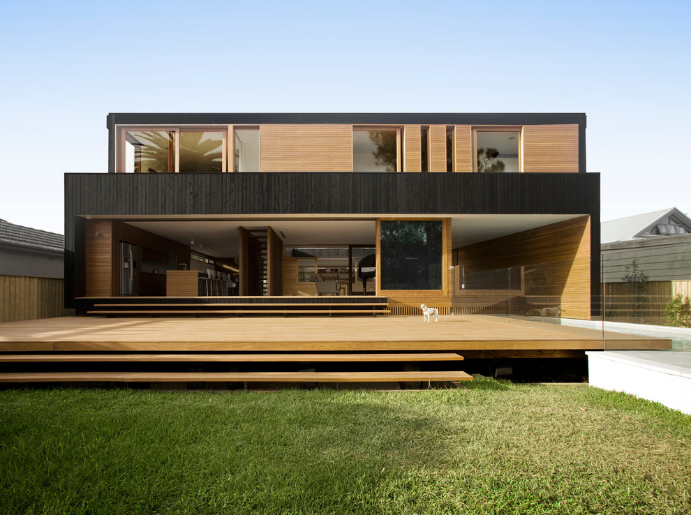 Photo of a large and black modern two floor detached house in Sydney with wood cladding, a flat roof and a metal roof.