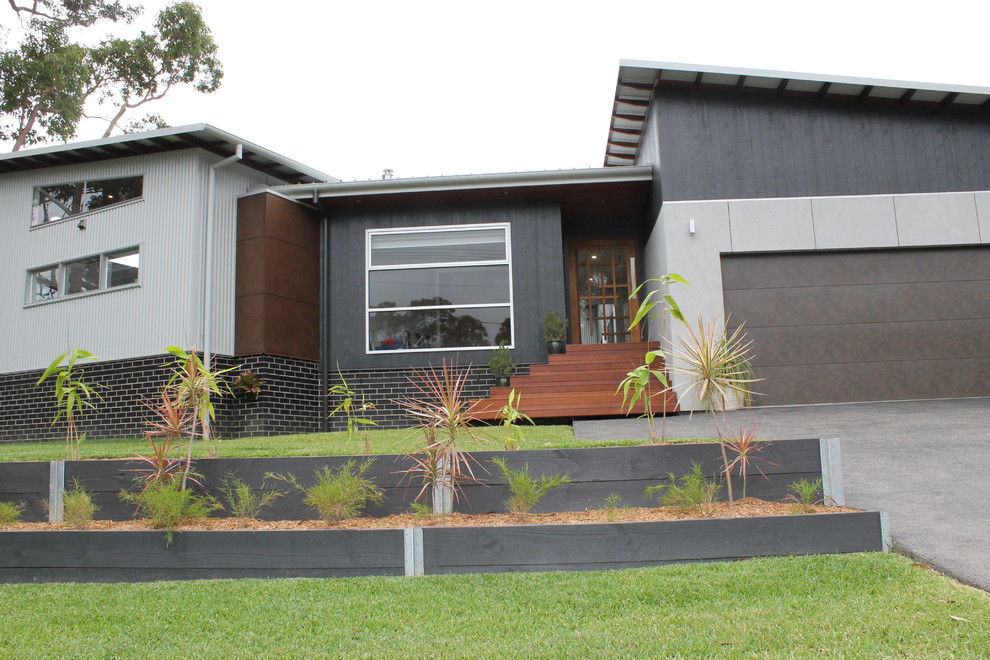 Photo of a medium sized and gey contemporary bungalow house exterior in Wollongong with concrete fibreboard cladding.