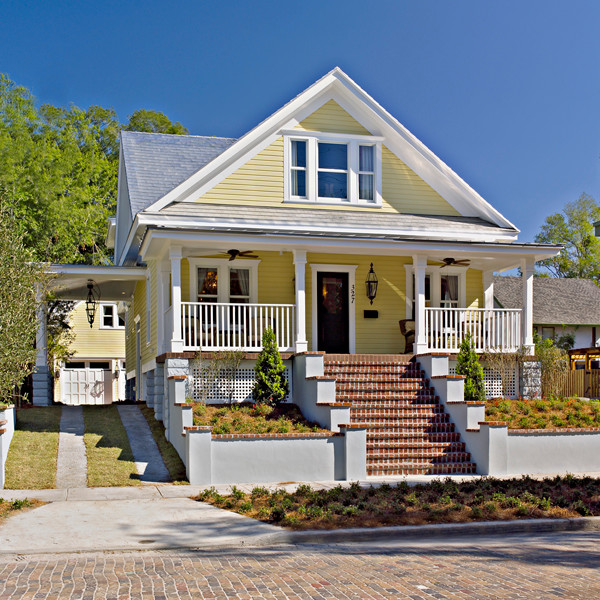 Cette image montre une façade de maison jaune craftsman de taille moyenne et à un étage avec un revêtement en vinyle et un toit à croupette.