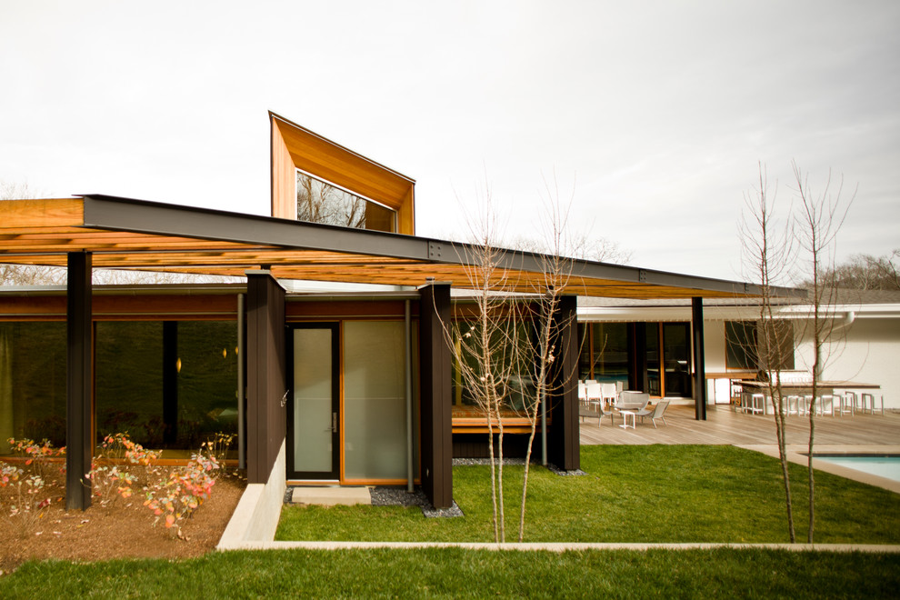 Modelo de fachada de casa negra minimalista grande de una planta con revestimiento de madera y tejado de un solo tendido