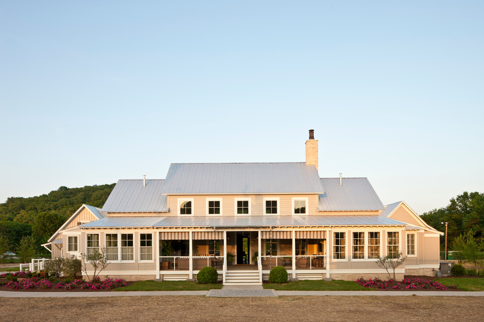 Foto della facciata di una casa grande beige country a due piani con rivestimento in legno e tetto a padiglione
