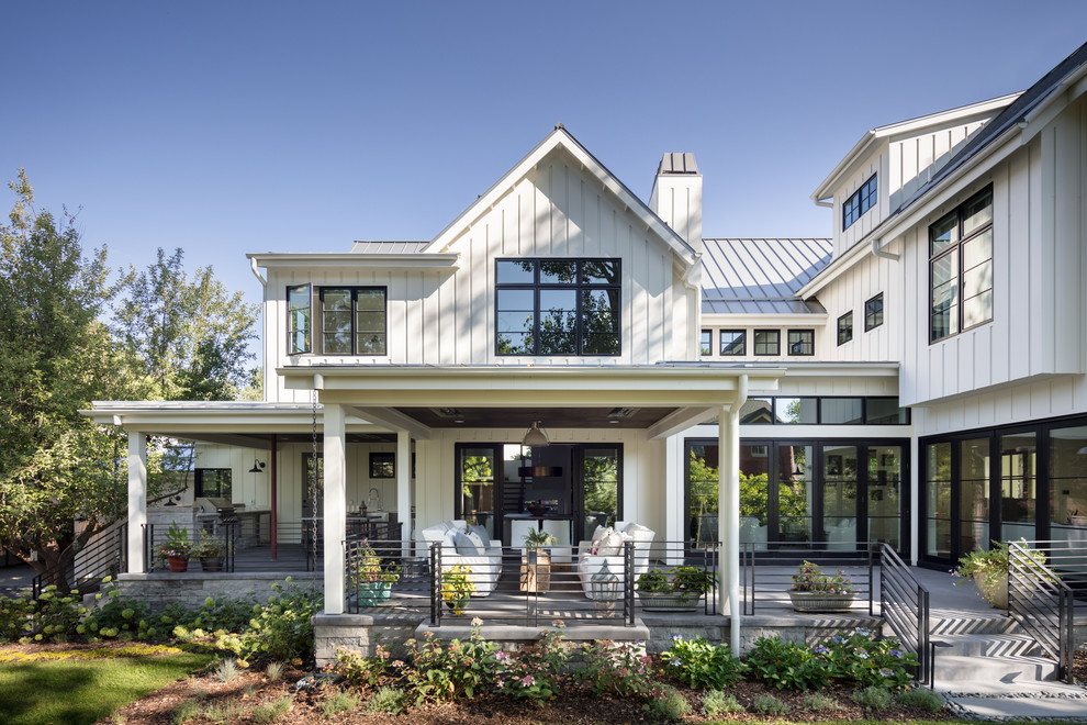 Cette photo montre une façade de maison blanche nature en bois à un étage avec un toit à deux pans et un toit en métal.