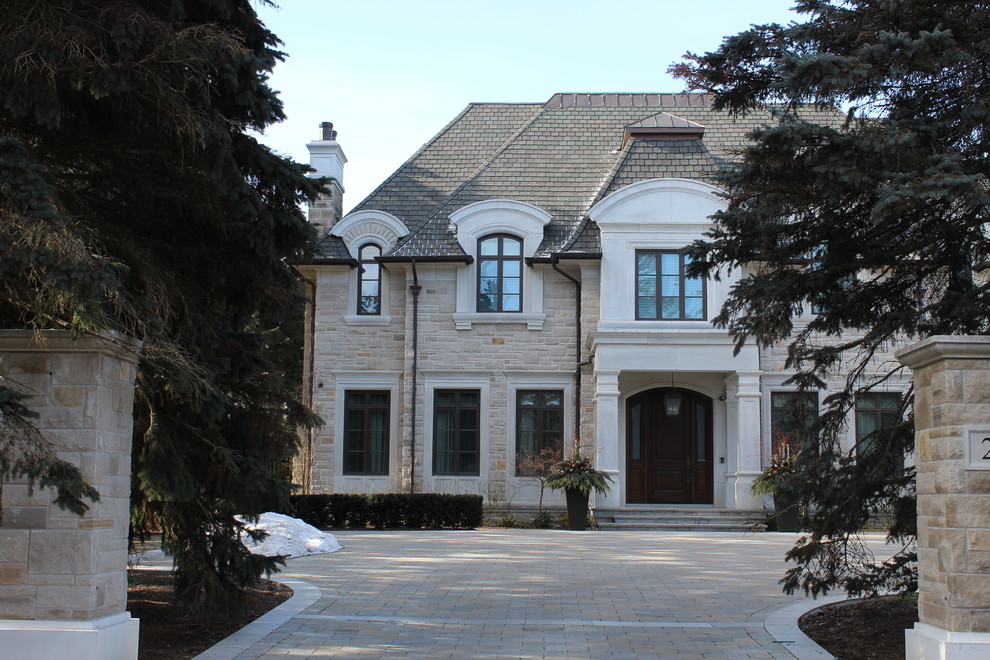 Immagine della villa grande beige classica a due piani con rivestimento in pietra, tetto a padiglione e copertura in tegole