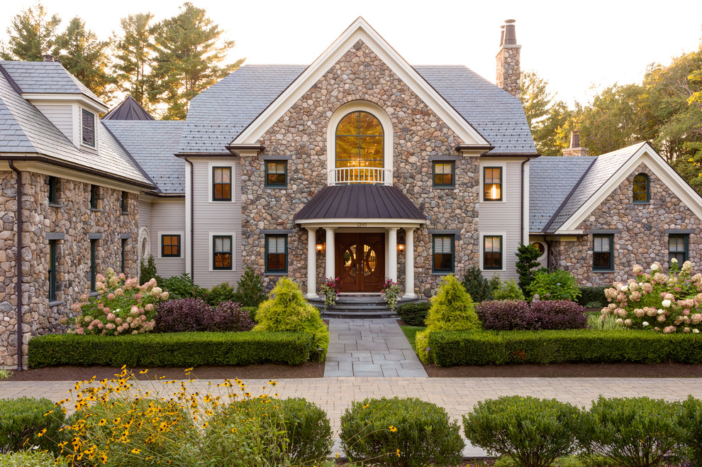Imagen de fachada de casa multicolor clásica de dos plantas con revestimiento de piedra y tejado de teja de madera