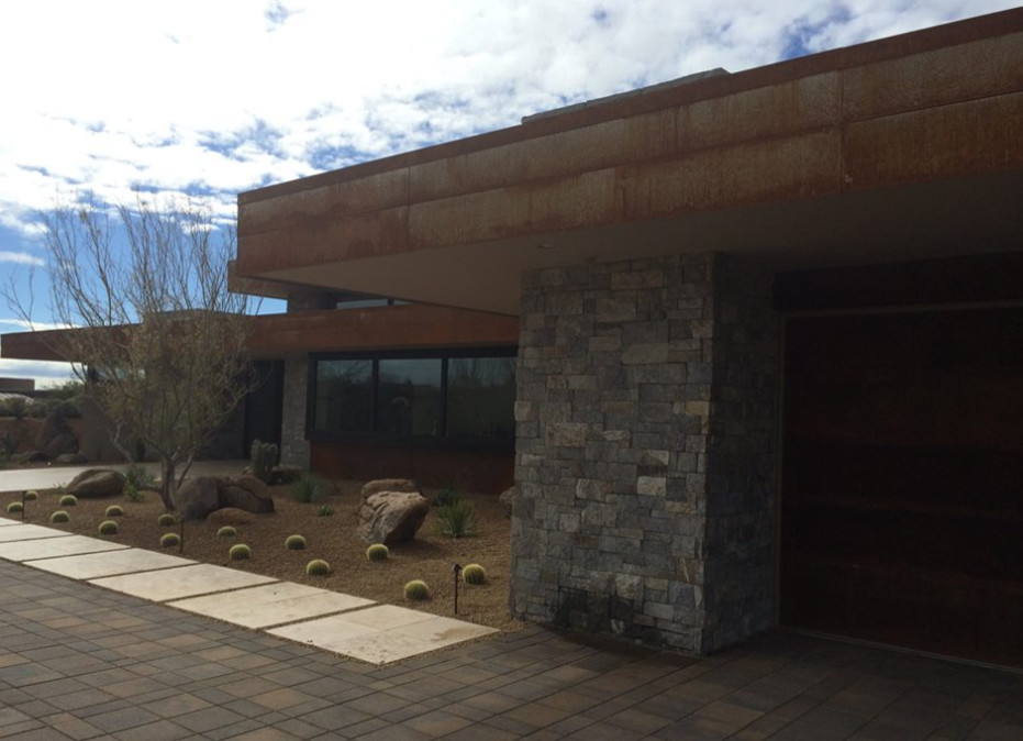 Large and gey modern bungalow house exterior in Phoenix with stone cladding and a flat roof.