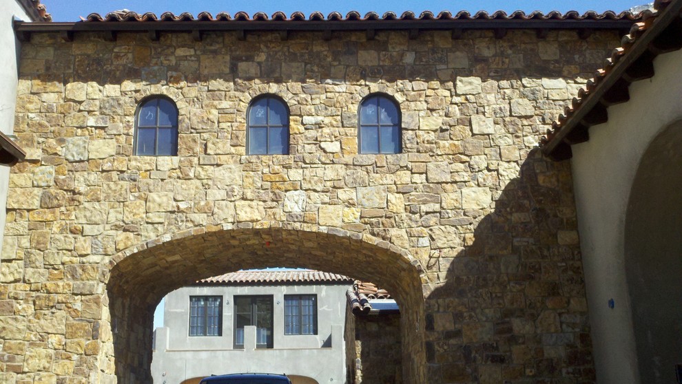 Foto della facciata di una casa grande beige mediterranea a due piani con rivestimento in pietra e tetto a mansarda