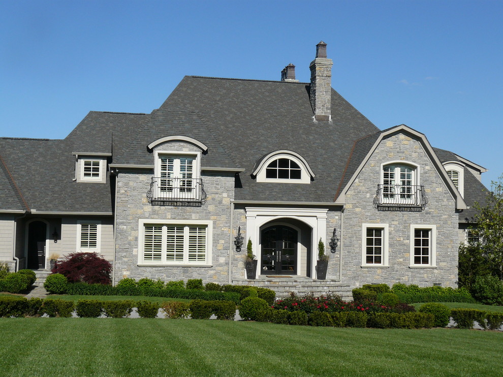 Modelo de fachada de casa gris de estilo americano grande de dos plantas con revestimiento de piedra, tejado a la holandesa y tejado de teja de madera