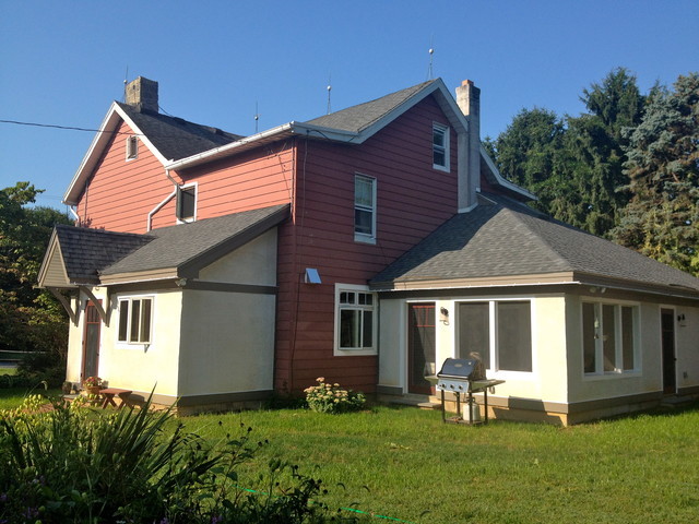 Diseño de fachada multicolor de estilo de casa de campo grande de dos plantas con revestimientos combinados y tejado a la holandesa