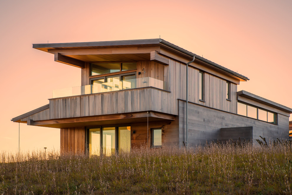 Inspiration pour une façade de maison marron design en bois à un étage avec un toit en appentis.