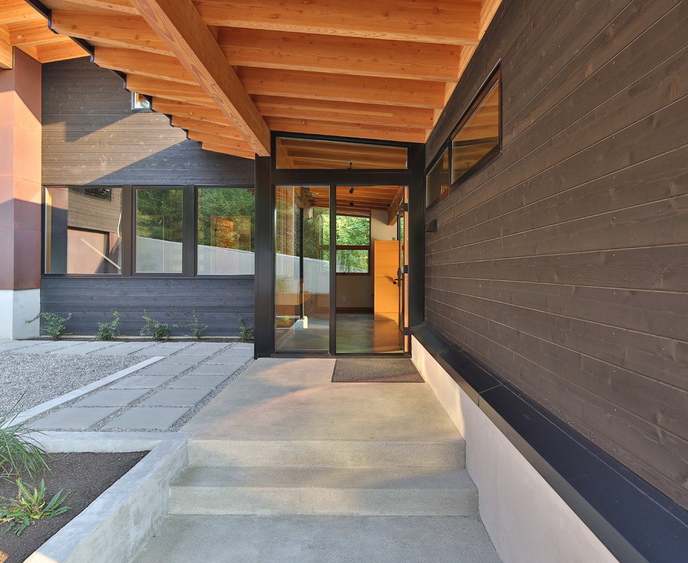 Inspiration pour une façade de maison noire minimaliste de taille moyenne et à niveaux décalés avec un revêtement mixte, un toit en appentis et un toit en métal.