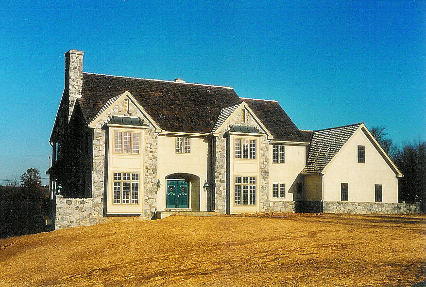 Cette image montre une façade de maison grise en pierre à deux étages et plus avec un toit à quatre pans.