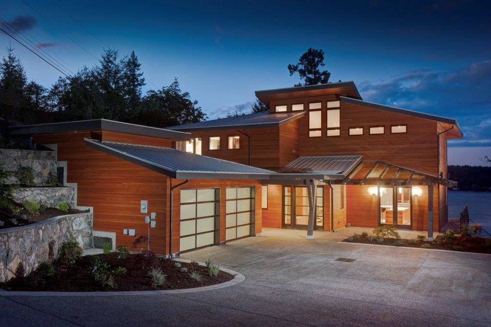 Photo of a large and brown contemporary house exterior in Vancouver with three floors, wood cladding and a lean-to roof.