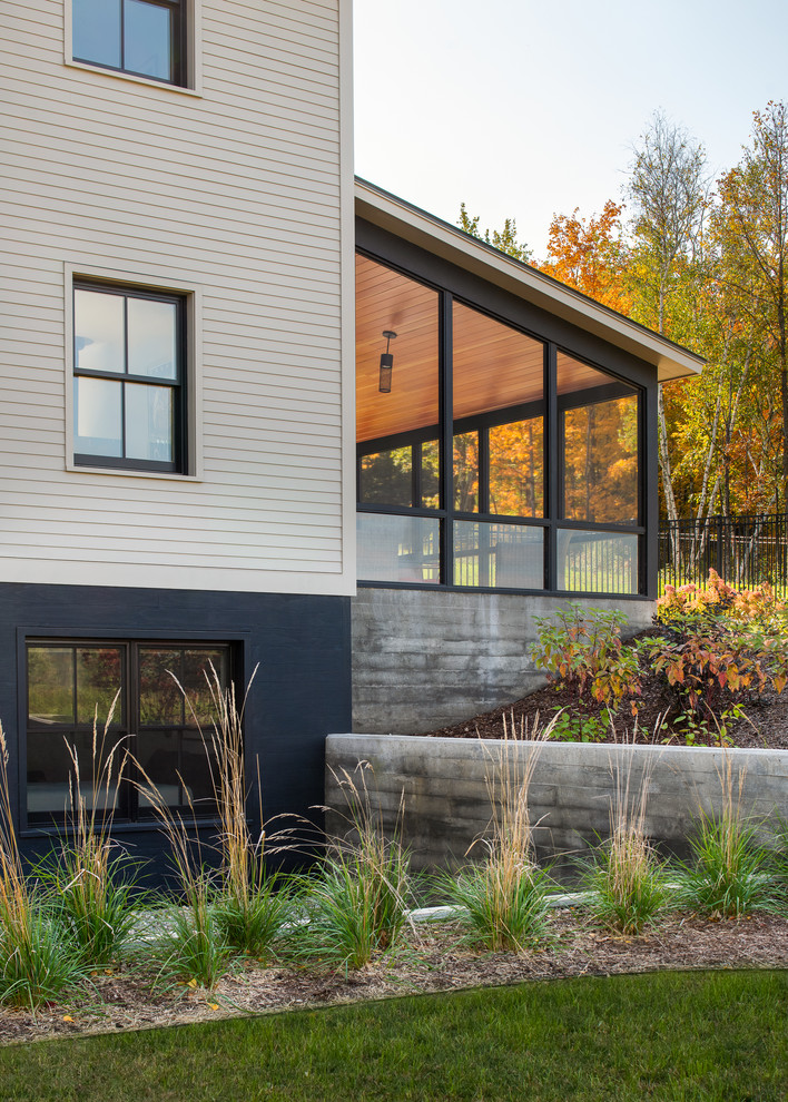 Imagen de fachada de casa beige de estilo de casa de campo de tamaño medio de tres plantas con revestimiento de hormigón, tejado a dos aguas y tejado de metal