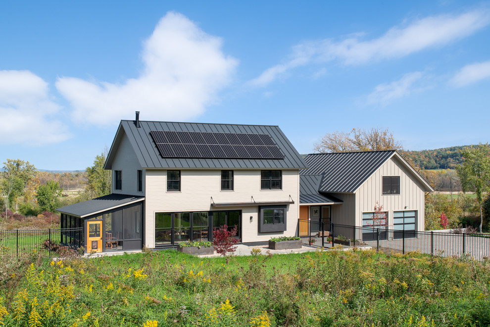 Imagen de fachada de casa beige de estilo de casa de campo de tres plantas con revestimiento de hormigón, tejado a dos aguas y tejado de metal