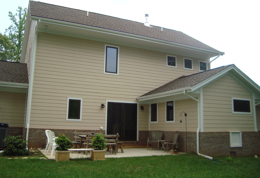 Cette photo montre une façade de maison jaune chic en panneau de béton fibré de taille moyenne et à un étage avec un toit à deux pans.