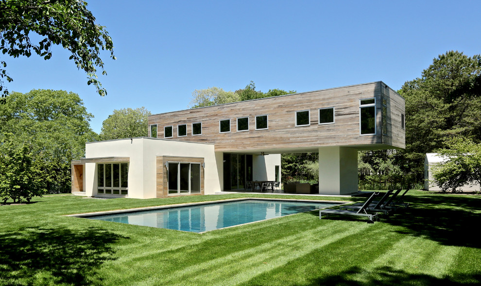 This is an example of a contemporary two floor detached house in New York with wood cladding and a flat roof.