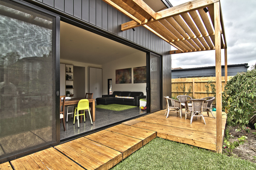 Medium sized and black industrial bungalow house exterior in Melbourne with metal cladding and a flat roof.