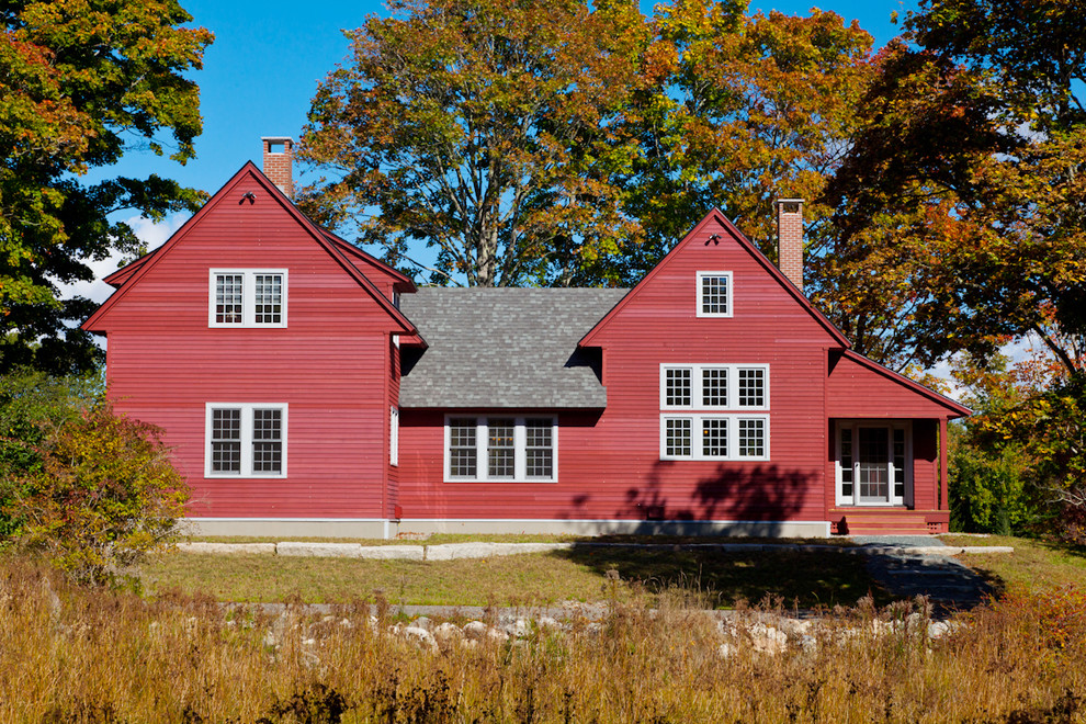 Photo of a red and large farmhouse two floor house exterior in Other with wood cladding and a pitched roof.