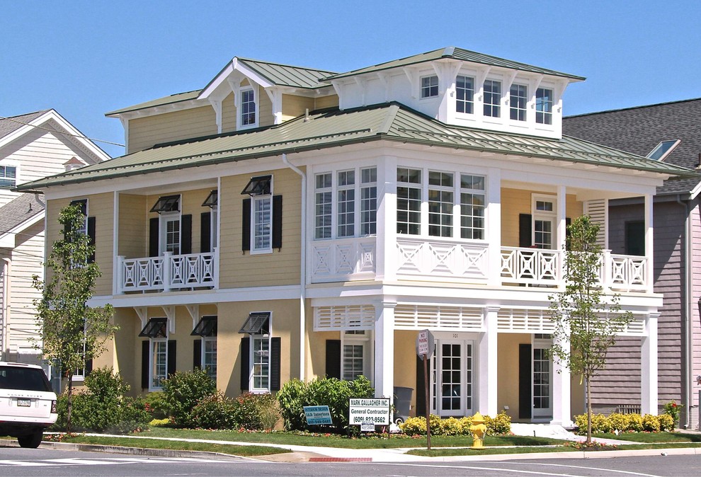 Idee per la facciata di una casa grande gialla tropicale a tre piani con rivestimento in stucco e tetto a padiglione