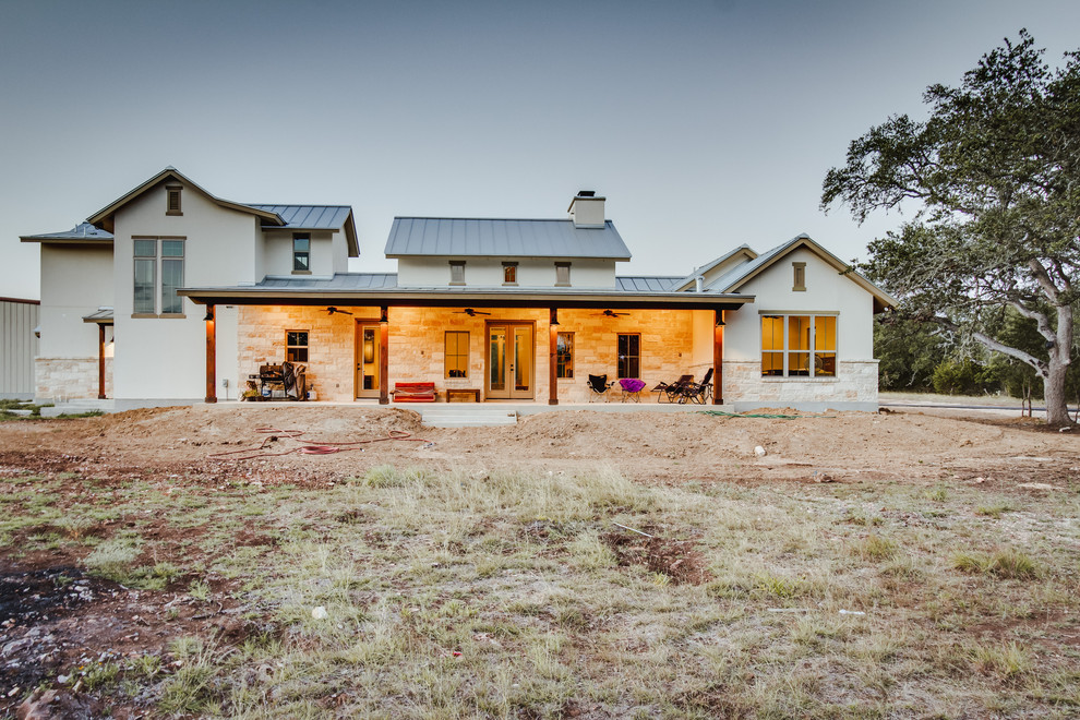 Mittelgroßes, Zweistöckiges Landhausstil Einfamilienhaus mit Putzfassade, beiger Fassadenfarbe, Satteldach und Blechdach in Austin